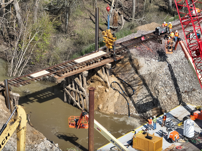 Crews work to replace a washed-out culvert with a bridge. 